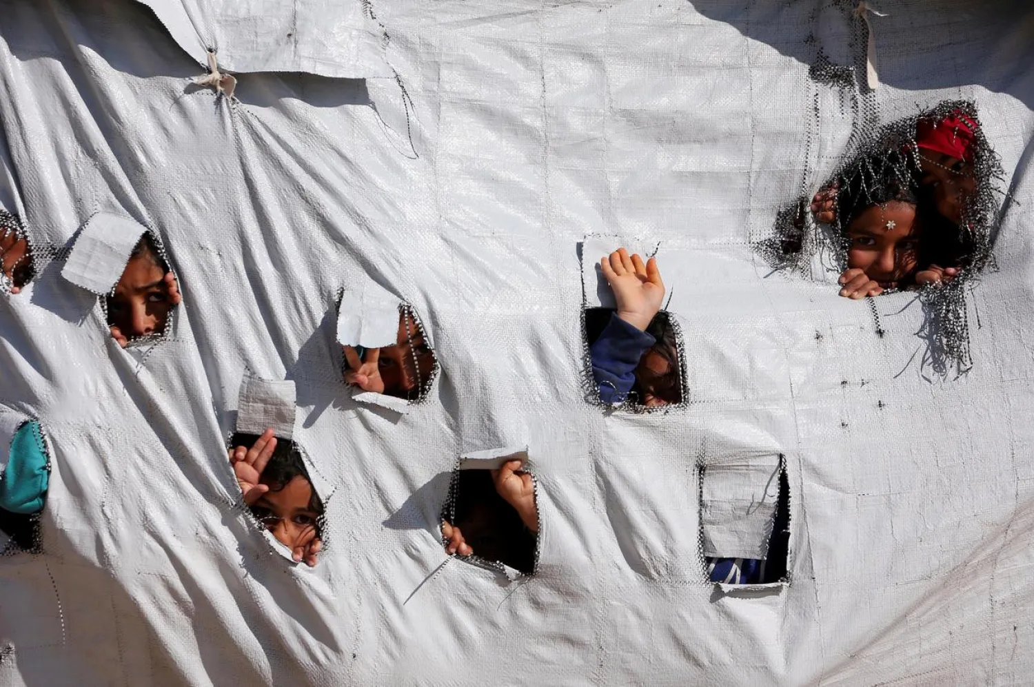 Children look through holes in a tent at al-Hol displacement camp (File Photo: Reuters)