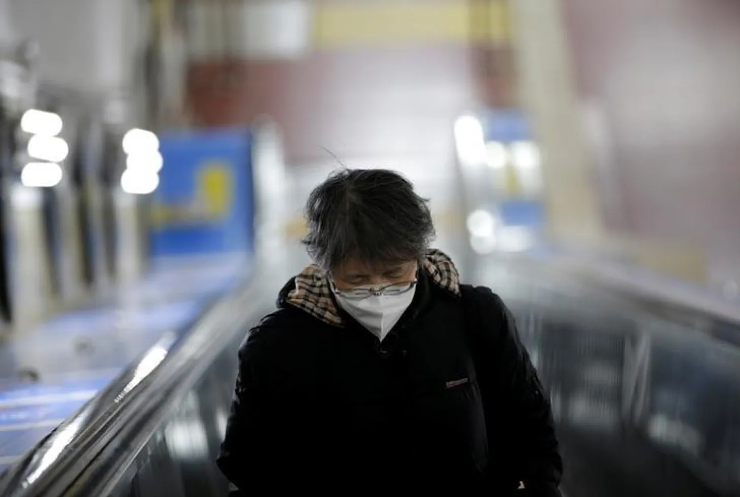 FILE PHOTO: A woman wearing a mask is pictured on the escalator at a subway station in Beijing, China January 21, 2020. REUTERS/Jason Lee
