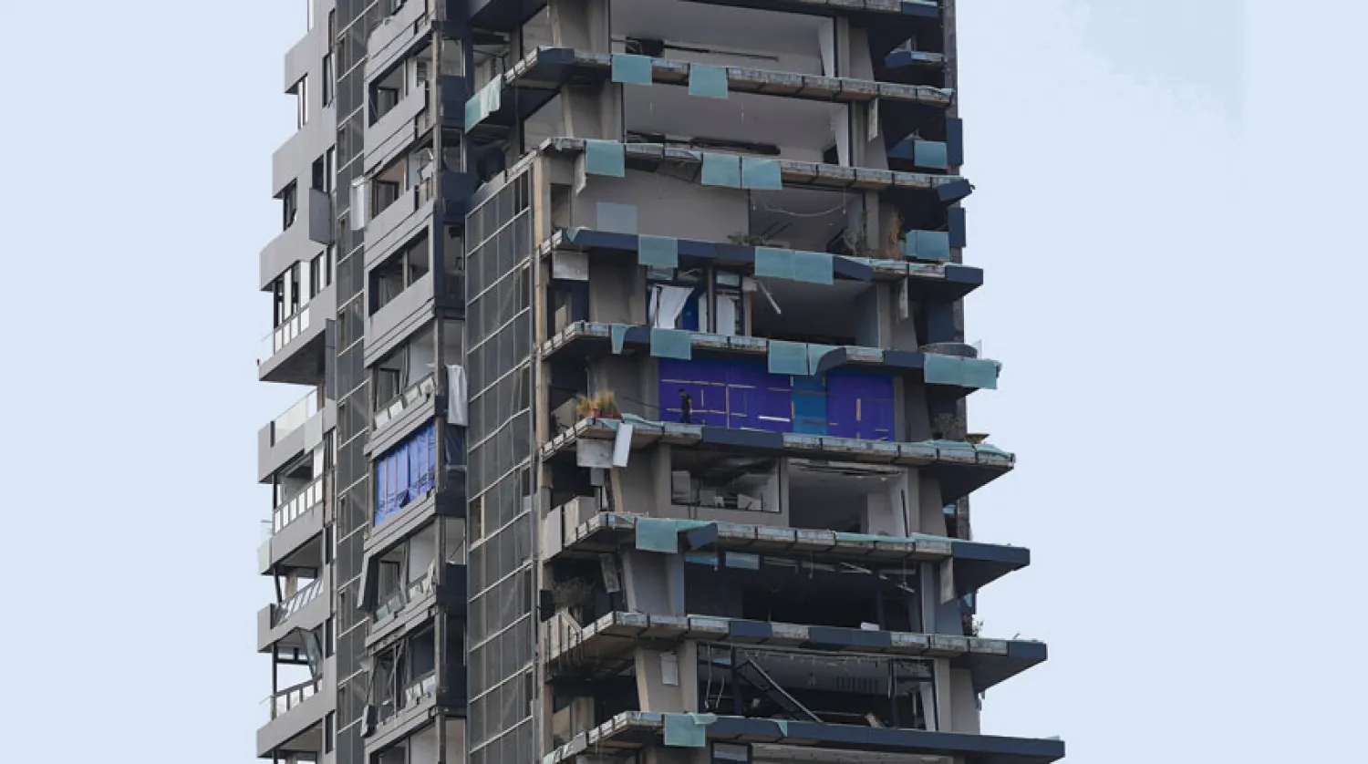 رجل يقف أمس على شرفة أحد المباني المتضررة بفعل انفجار مرفأ بيروت (رويترز)