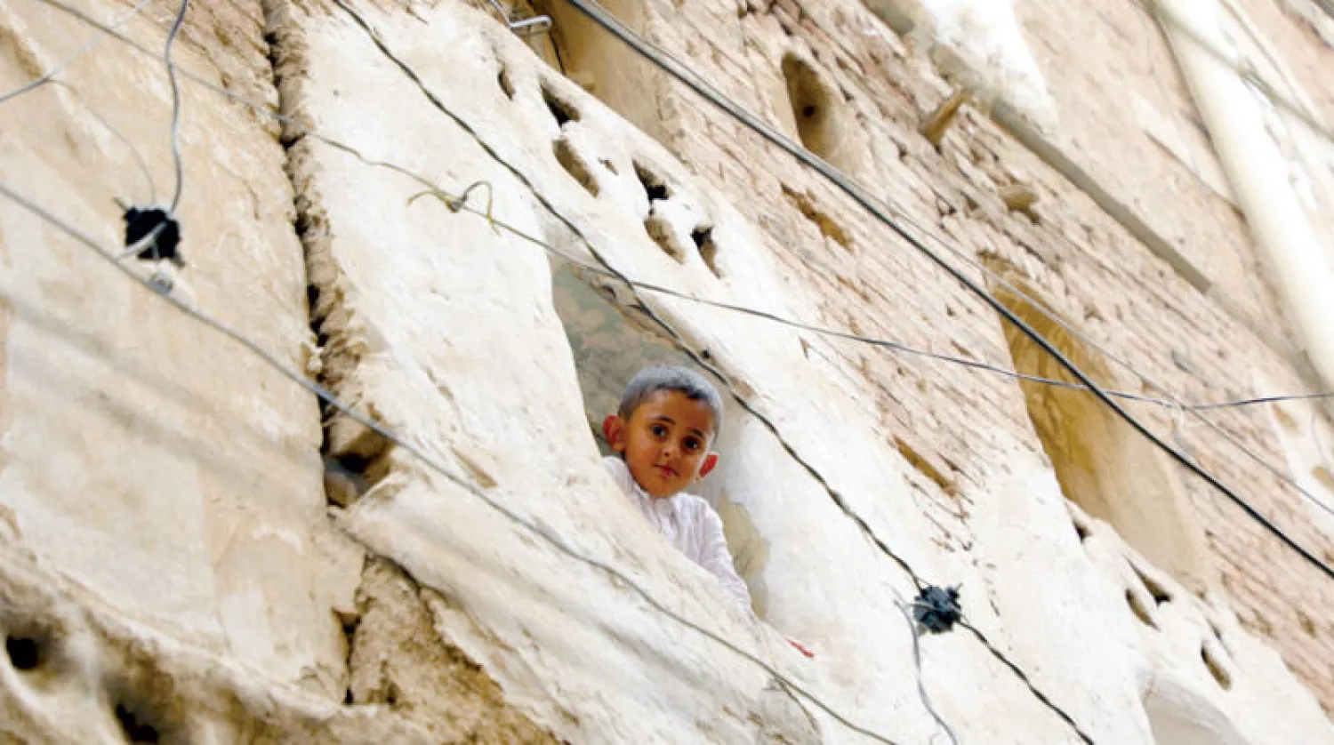 طفل يمني يطل من نافذة بمنزل في المدينة القديمة وسط صنعاء (أ.ف.ب)