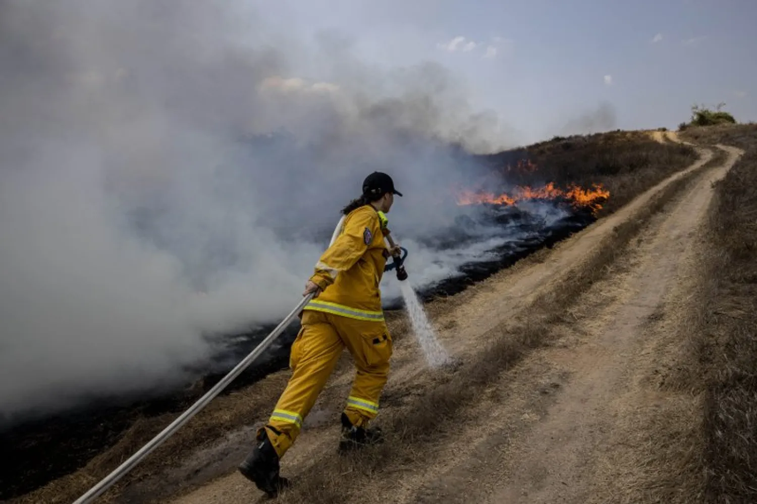 An Israeli firefighter attempts to extinguish a fire caused by a incendiary balloon launched by Palestinians from the Gaza Strip, on the Israeli side of the border between Israel and Gaza, near Or HaNer Kibbutz, Wednesday, Aug. 12, 2020. 