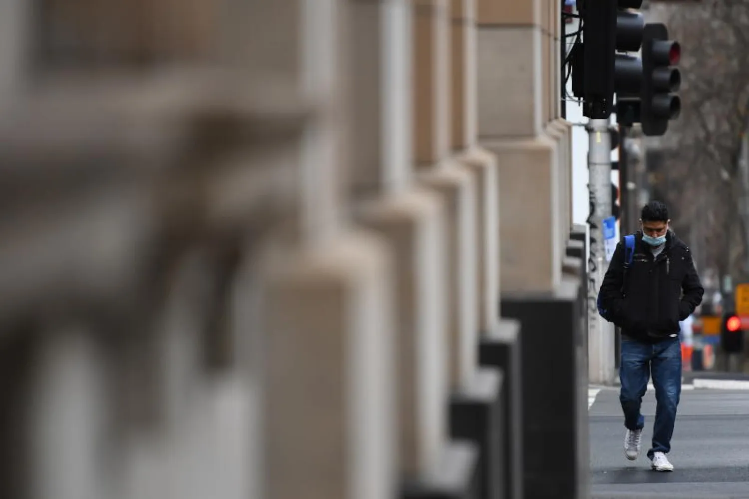 رجل يرتدي كمامة أثناء تجوله في شارع بملبورن في أستراليا (إ.ب.أ)