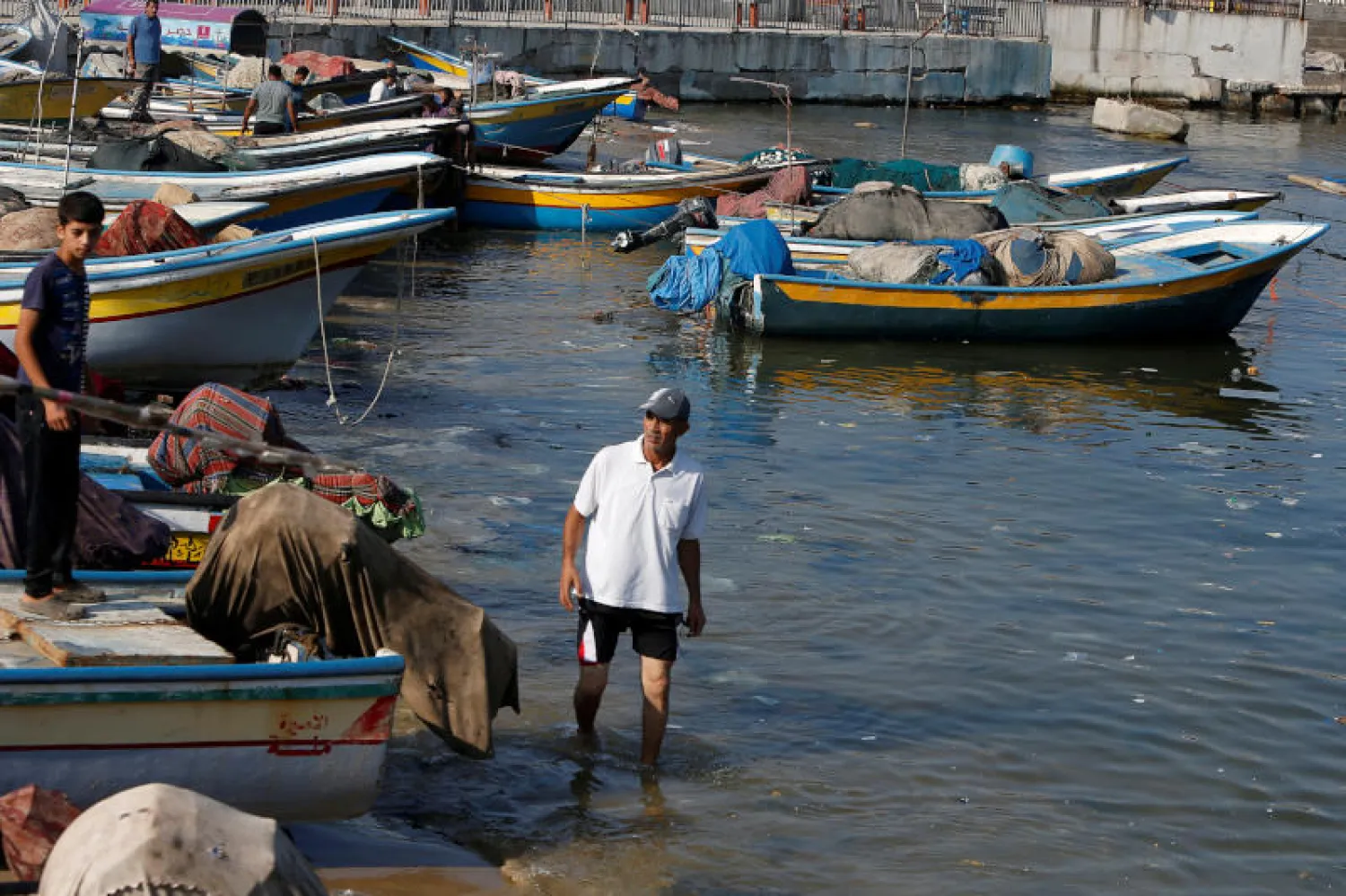 صياد يمشي وسط مراكب في ميناء غزة (رويترز)