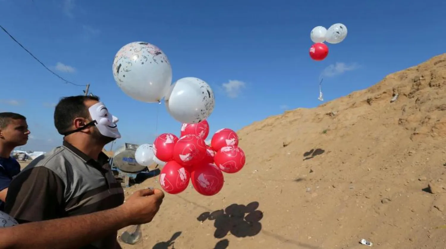 FILE PHOTO: Palestinians fly balloons loaded with flammable material to be thrown at the Israeli side, near the Israel-Gaza border in the central Gaza Strip, June 4, 2018. REUTERS/Ibraheem Abu Mustafa
