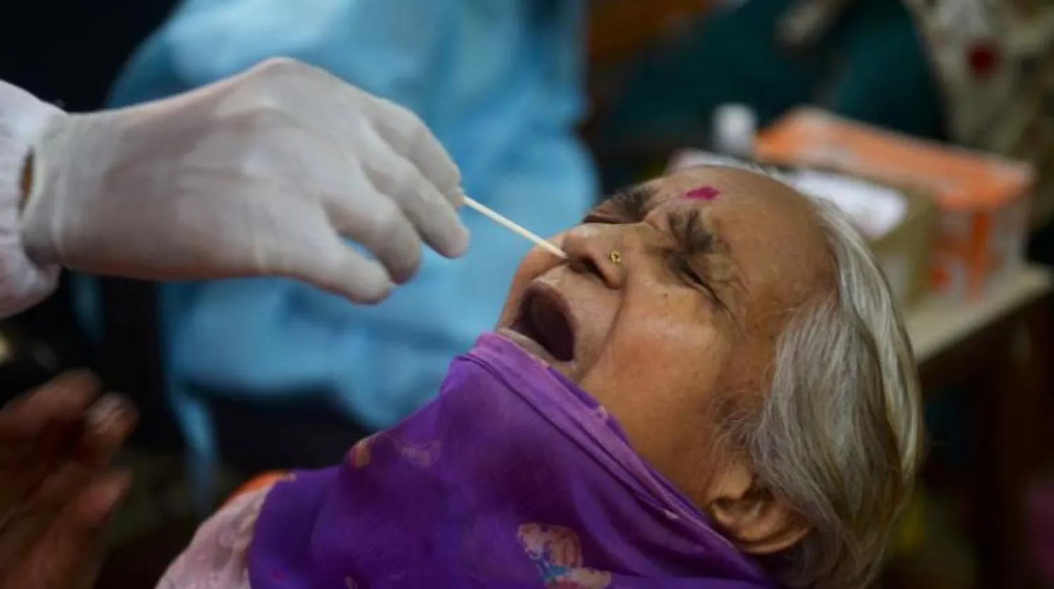 Bir sağlık çalışanı, Mumbai'deki bir test kampında koronavirüsü test etmek için bir sakinden örnek alıyor (AFP)