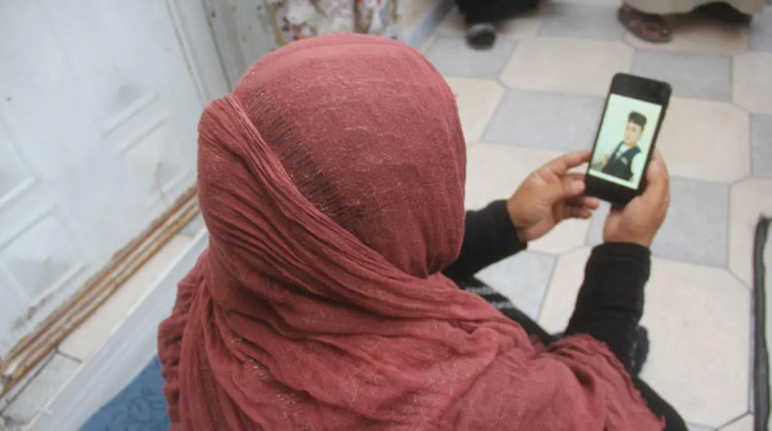 امرأة مع صورة ابنها على جهاز هاتف نقال (الشرق الأوسط)