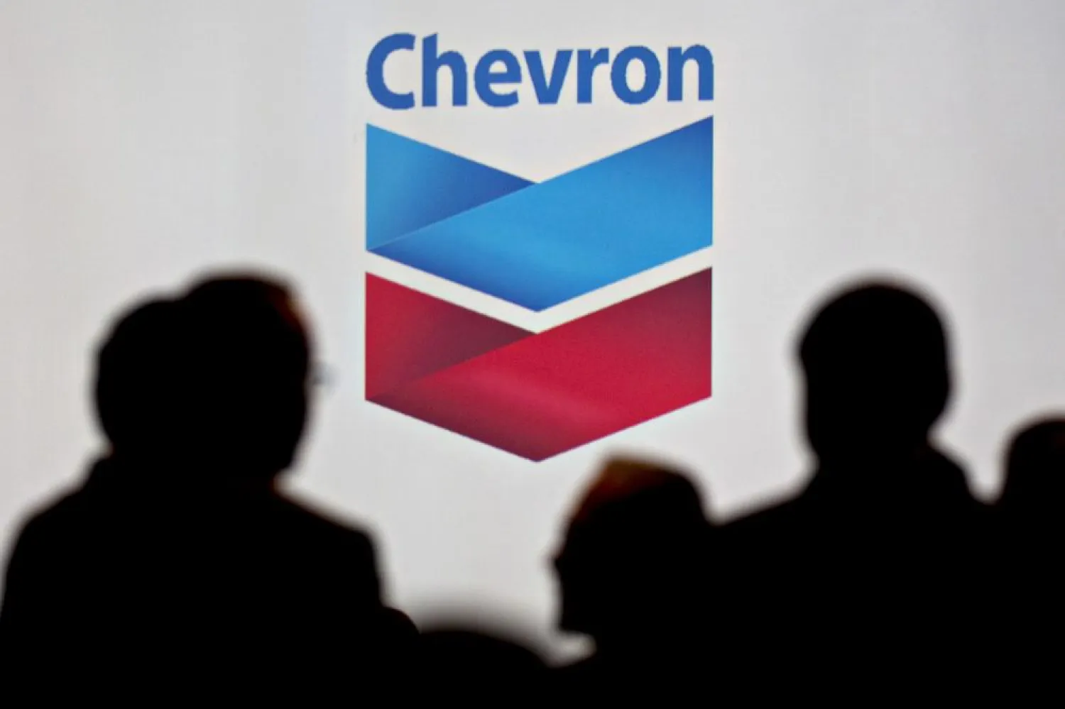 Attendees stand near Chevron signage during the World Gas Conference. Photo: Andrew Harrer/Bloomberg