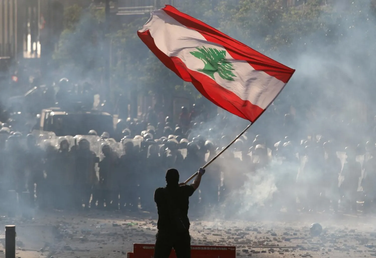 A demonstrator waves the Lebanese flag in front of riot police during protests in Beirut on August 8, 2020. (Reuters)