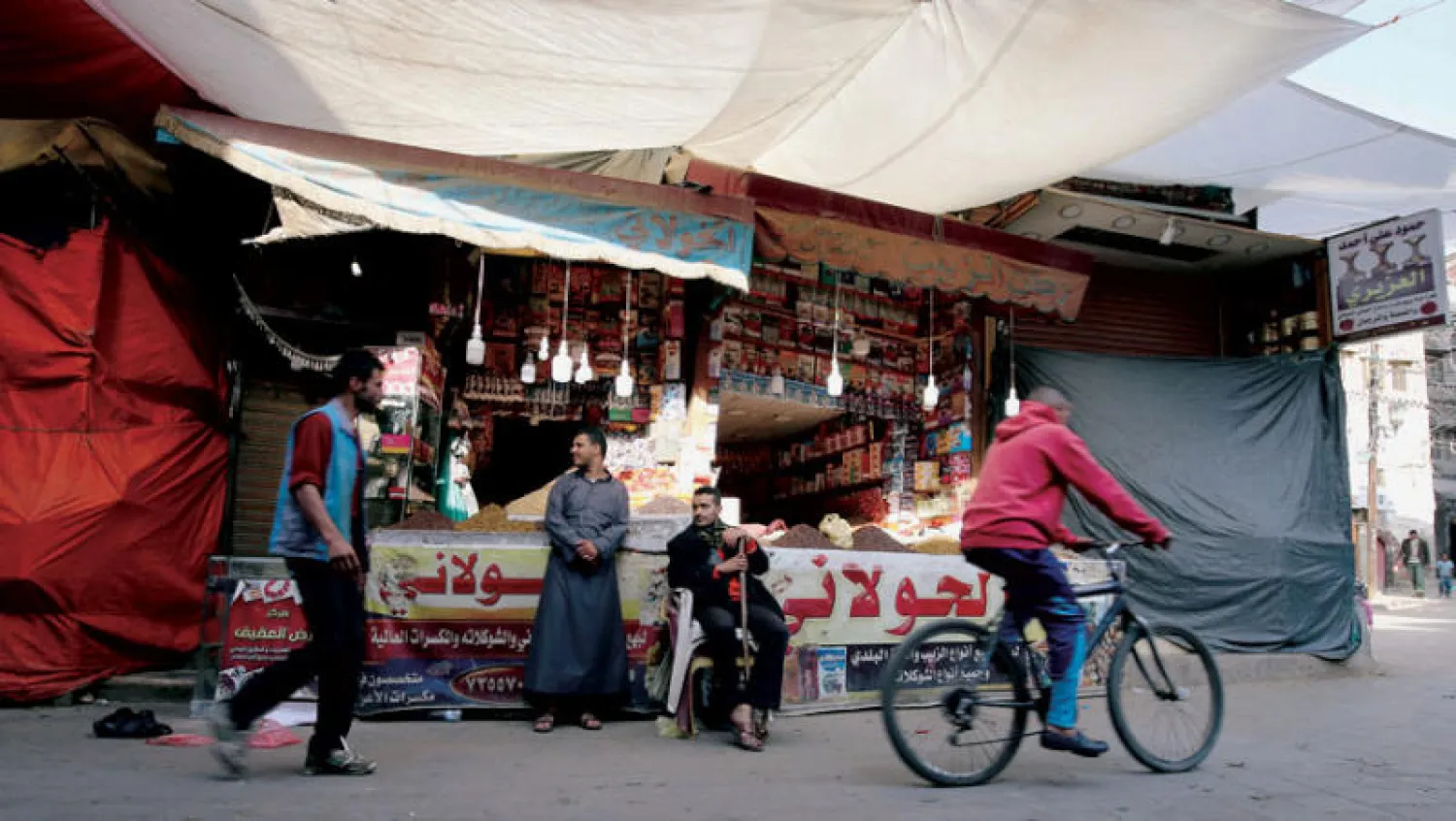 متسوقون أمام متجر في المدينة القديمة بصنعاء (رويترز)