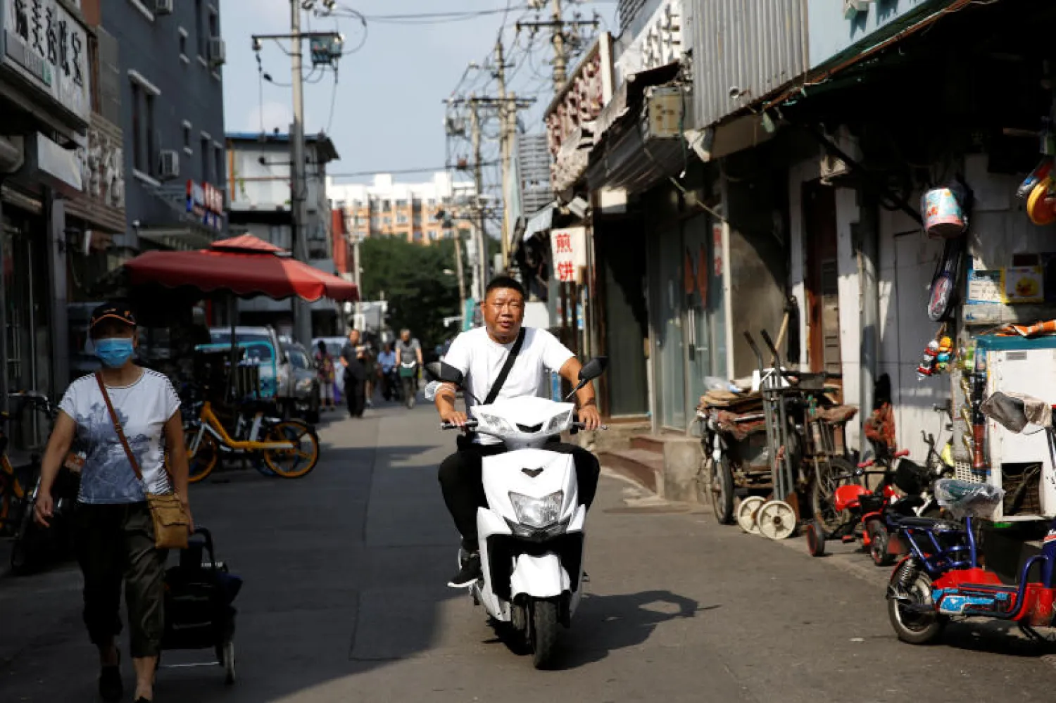 رجل يقود دراجة نارية من دون وضع كمامة في العاصمة الصينية بكين (رويترز)