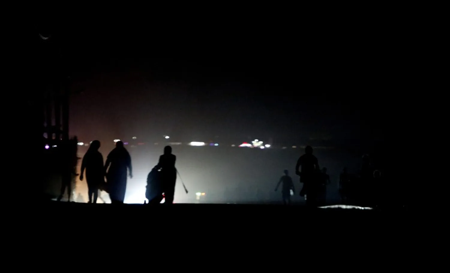 Palestinian residents walk in the Shati refugee camp in west Gaza City as the coastal enclave gets maximum four hours of electricity a day, Wednesday, Aug. 19, 2020. (AP Photo/Hatem Moussa)