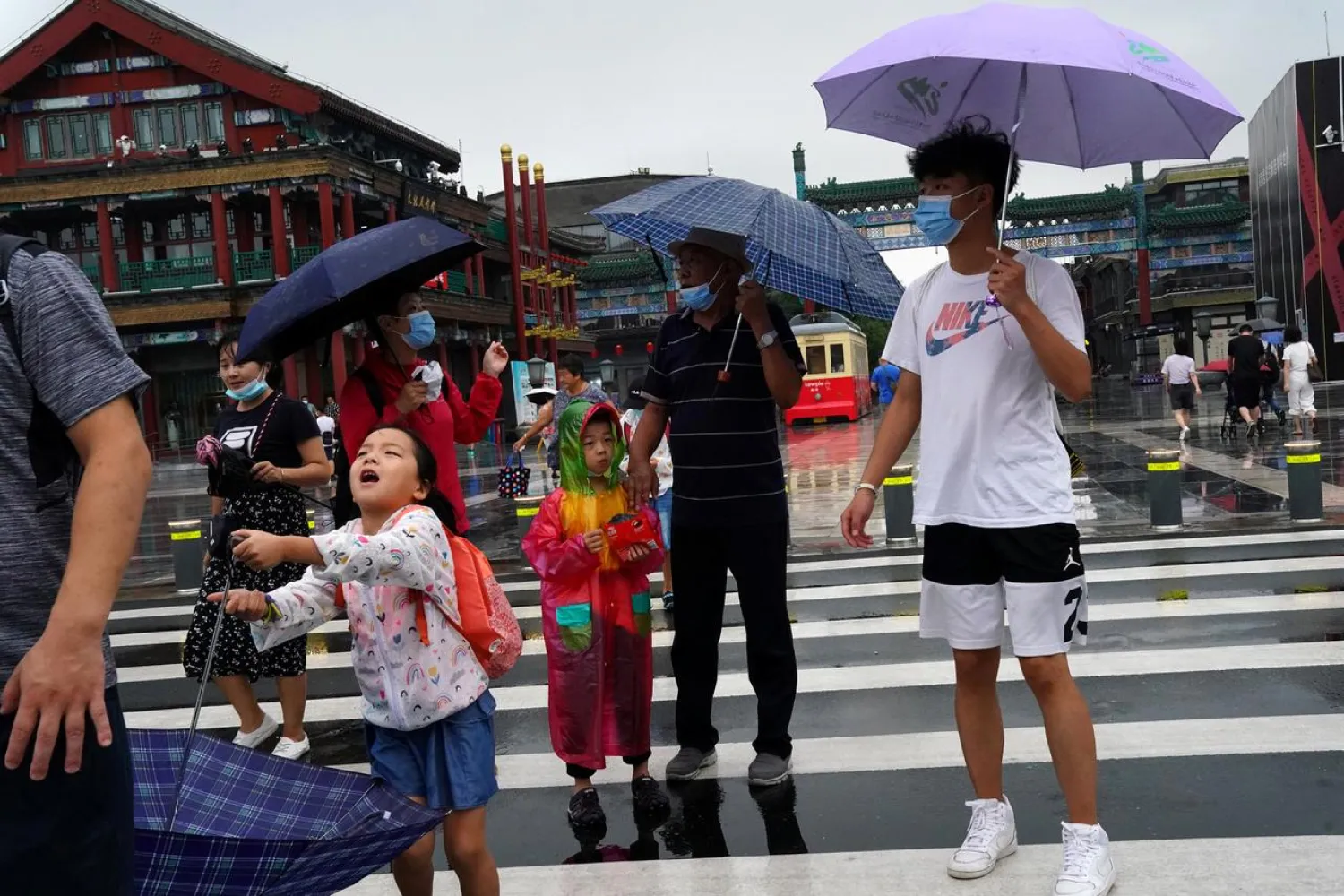 People wearing face masks walk near Qianmen Street on a rainy day, following the coronavirus disease (COVID-19) outbreak, in Beijing, China August 18, 2020. (Reuters)
