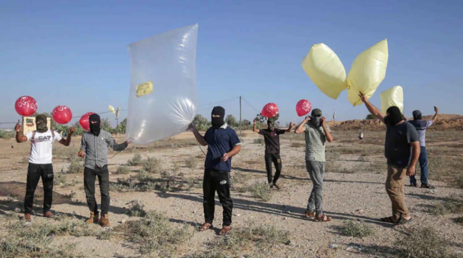 فلسطينيون يلوحون بالبالونات الحارقة بالقرب من رفح (أ.ف.ب)