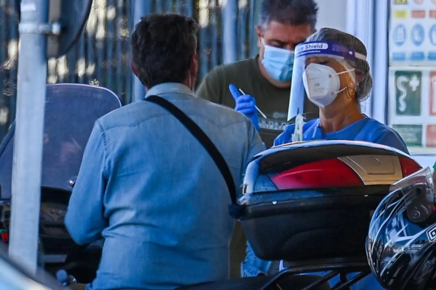 سائح على دراجة نارية عائداً من سردينيا بالعبّارة يخضع لمسحة إلزامية لفيروس «كورونا» في ميناء تشيفيتافيكيا شمال غرب روما (أ.ف.ب)