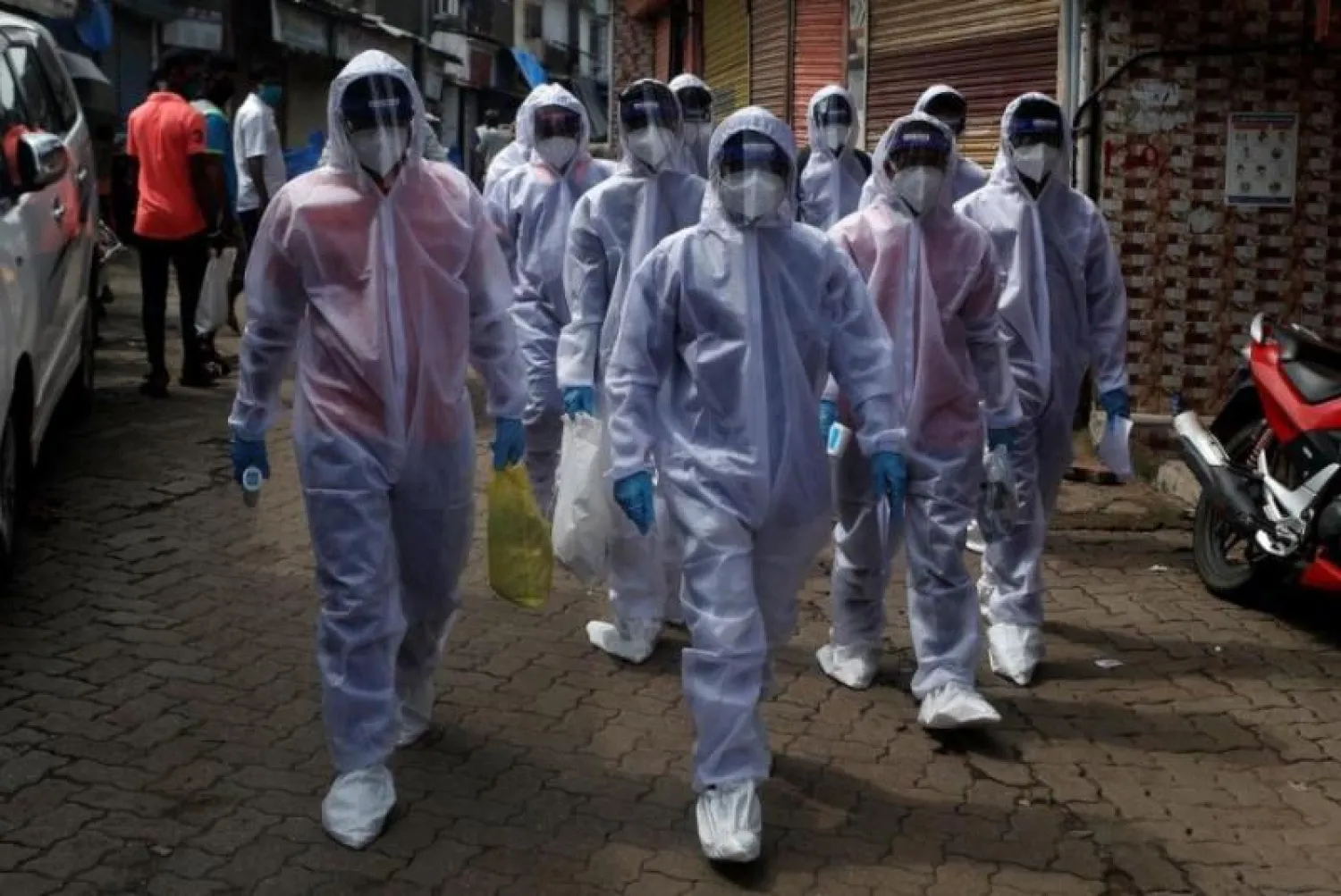 عمال الرعاية الصحية يرتدون معدات الحماية الشخصية في معسكر فحص لمرض فيروس «كورونا» في مومباي (رويترز)