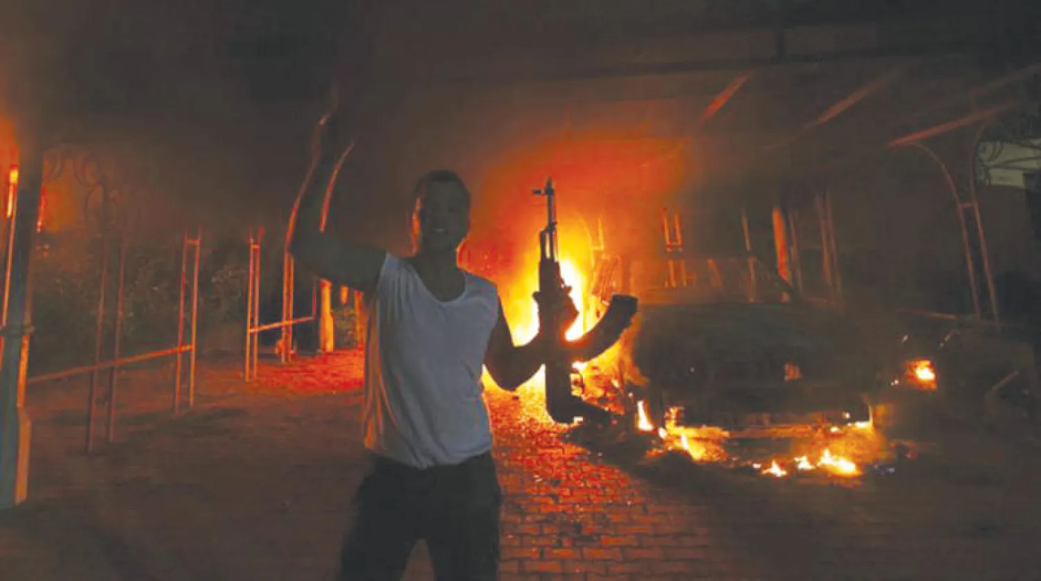 رجل مسلح بينما تتصاعد النيران في القنصلية الأميركية في بنغازي بعد هجوم في 11 سبتمبر 2012 (رويترز)