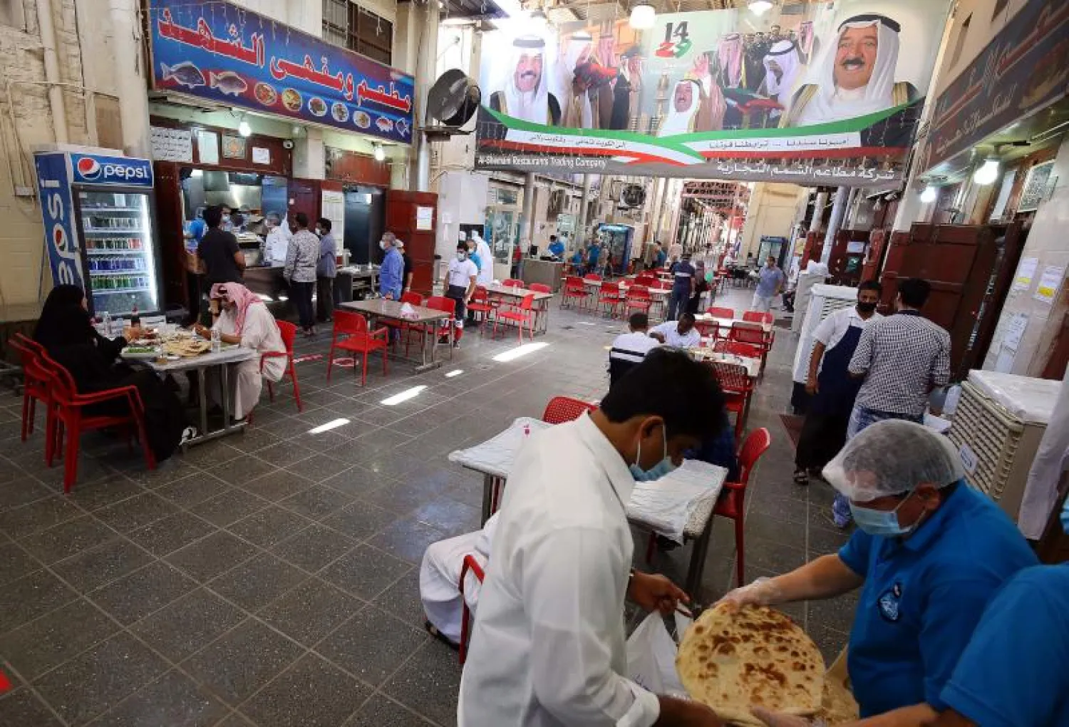 أشخاص يتناولون الغداء في أحد المطاعم بالكويت (أ.ف.ب)