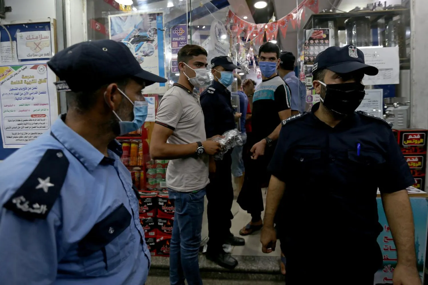 Palestinian police officers guard outside a shop after Gaza reported its first cases of COVID-19 in the general population, in the southern Gaza Strip August 24, 2020. (Reuters)