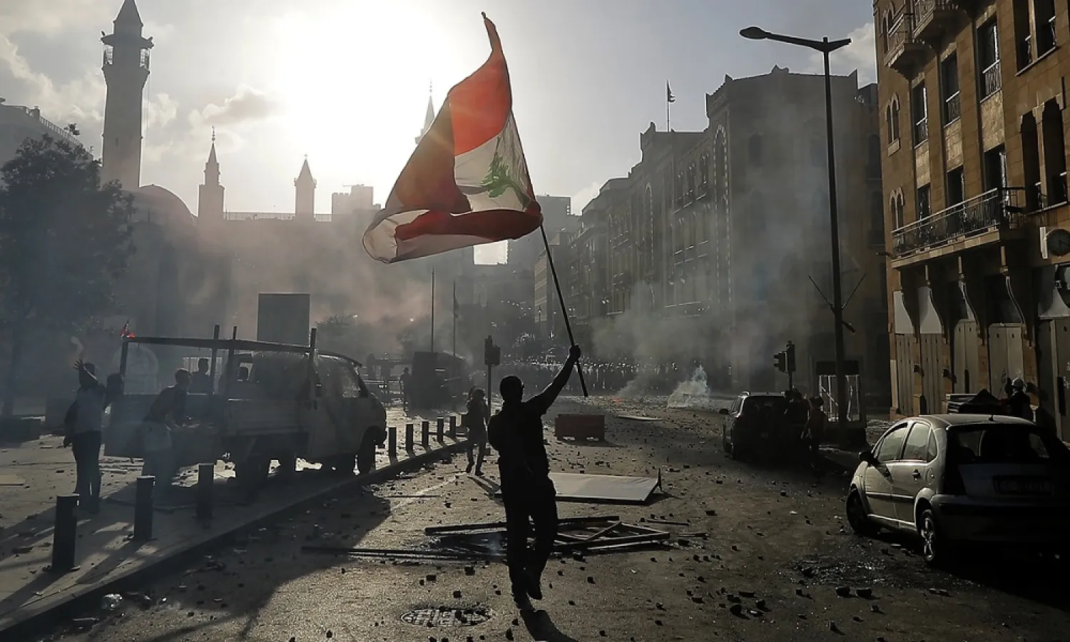 A Lebanese protester waves the national flag during clashes with security forces in downtown Beirut, Lebanon days after the port blast. (AFP)
