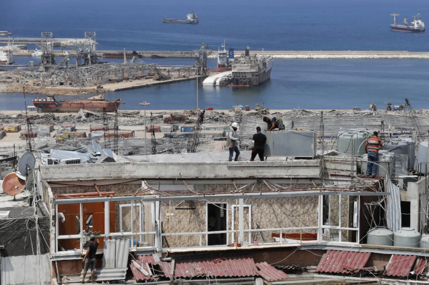 عمال يصلحون خزانات المياه والشقق المتضررة المطلة على موقع انفجار بيروت (أ.ب)