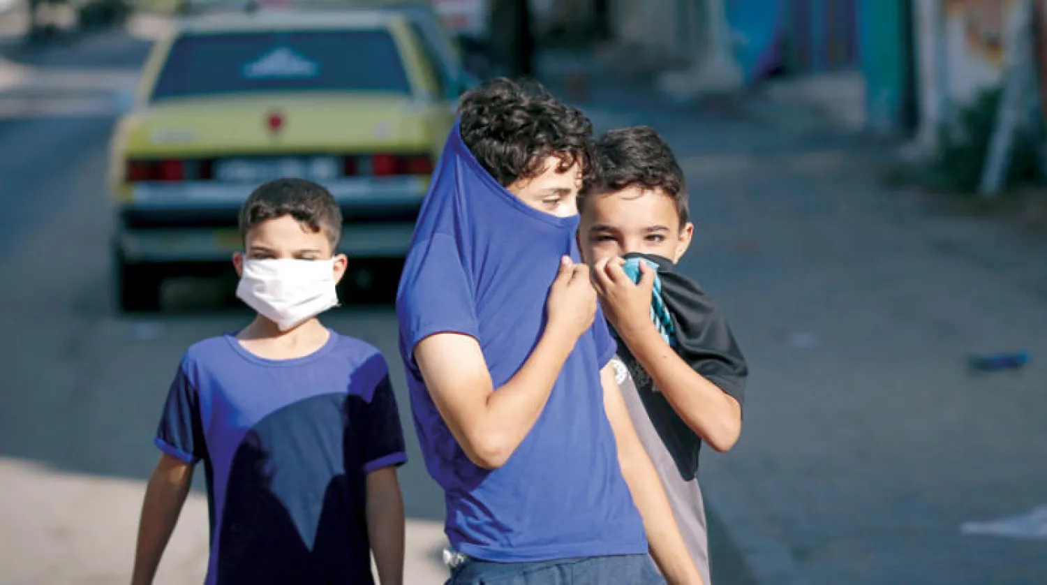 أطفال فلسطينيون يغطون وجوههم وقاية من الفيروس في أحد شوارع غزة أمس (أ.ف.ب)