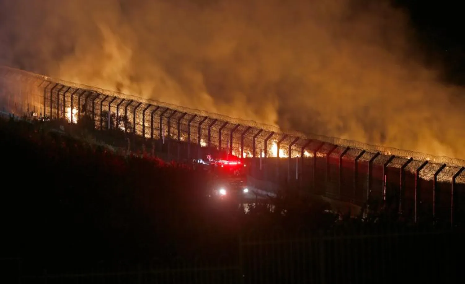 رجال إطفاء إسرائيليون يحاولون السيطرة على حريق على السياج الحدودي مع سوريا (أ.ف.ب)