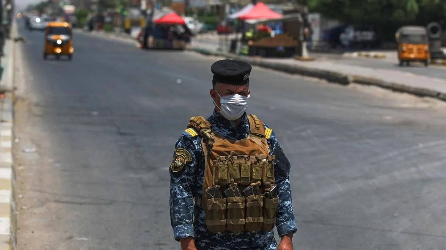A member of the Iraqi security forces stands guard at a checkpoint, enforcing a curfew due to the COVID-19 pandemic, in Baghdad's Sadr City suburb on May 31, 2020. (AFP)
