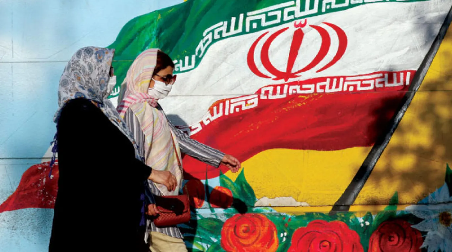 إيرانيتان تعبران أمام لوحة جدارية للعلم الإيراني في طهران يوليو الماضي (إ.ب.أ)