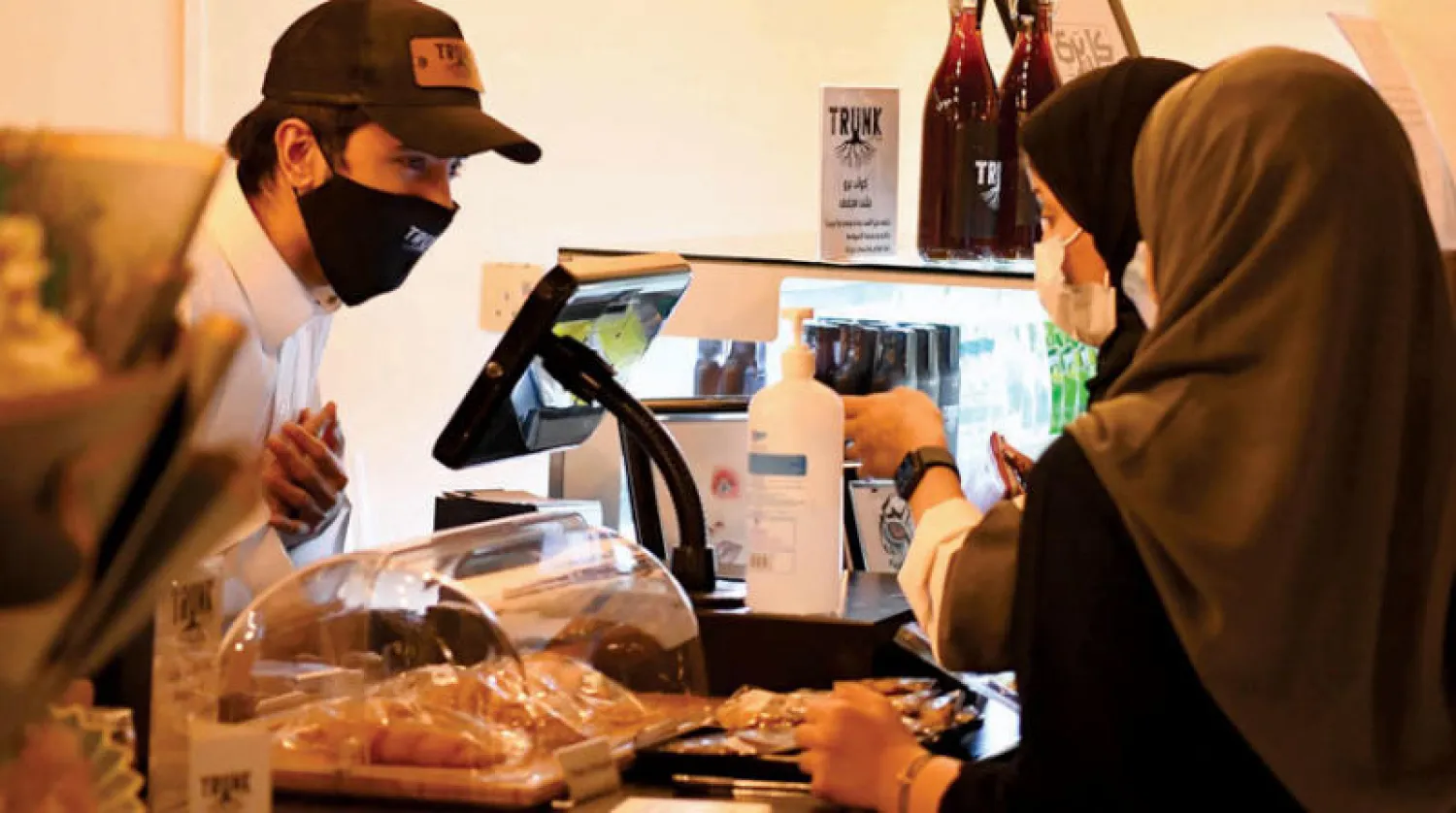 مشترٍ وبائعتان بكمامات في أحد مطاعم السعودية (تصوير: بشير صالح)