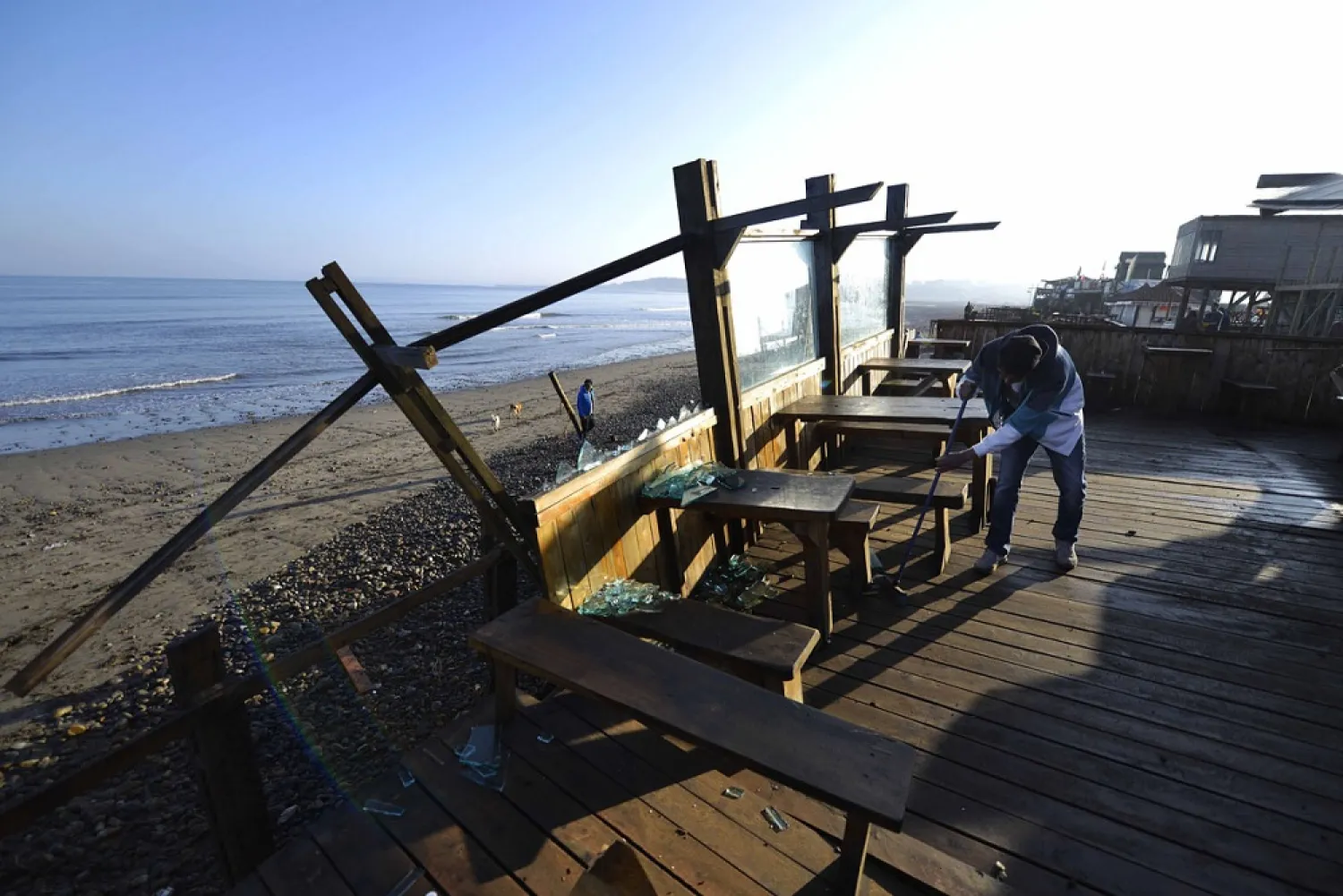 A man sweeps broken glasses at a beach-side bar damaged by an earthquake-triggered tsunami in Concon, Chile, Thursday, Sept. 17, 2015. (AP)