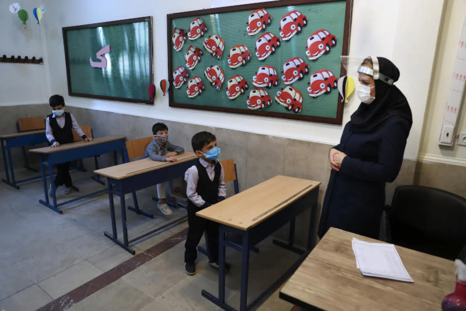 مدرّسة وطلاب في إحدى مدارس طهران يرتدون كمامات للوقاية من فيروس «كورونا» (أ.ب)