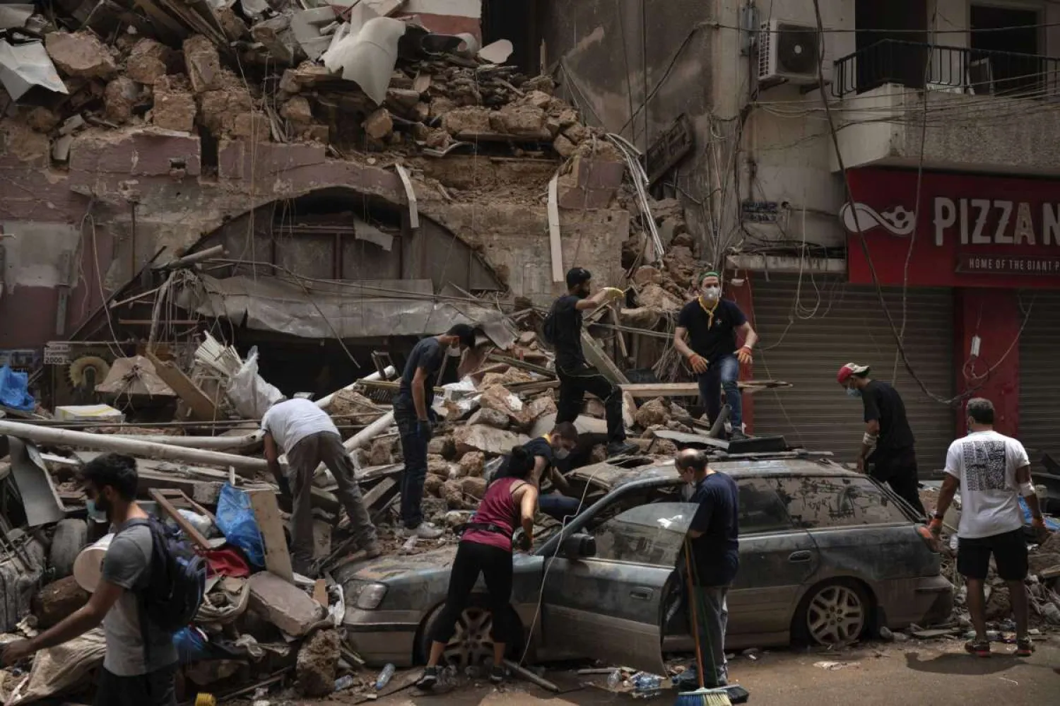 In this Friday, Aug. 7, 2020 file photo, people remove debris from a house damaged by the Aug. 4 explosion that hit the seaport of Beirut, Lebanon. It was 20 minutes before 6:08 p.m. when the Beirut fire brigade received the call from an employee at the nearby port reporting a big fire. Ten firefighters, including a female paramedic, piled into a fire engine and an ambulance and raced toward the scene, and their ultimate death. (AP Photo/Felipe Dana, File)