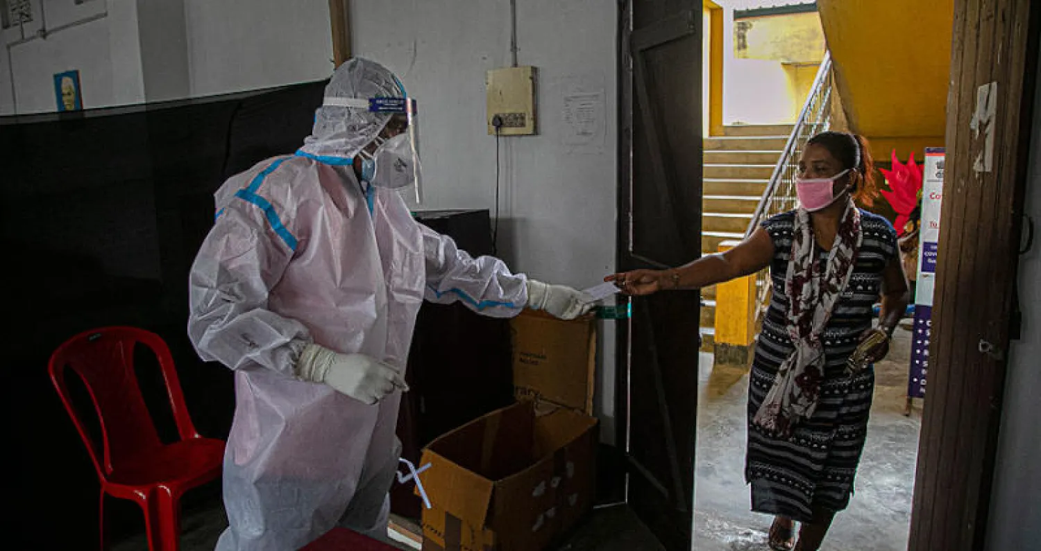 عامل صحة هندي يستلم مسحة «كورونا» من مصابة محتملة في غوهاتي أمس (أ.ب)