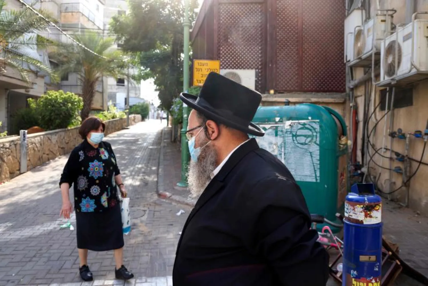 مارة يرتدون الأقنعة الواقية في إسرائيل (أ.ف.ب)