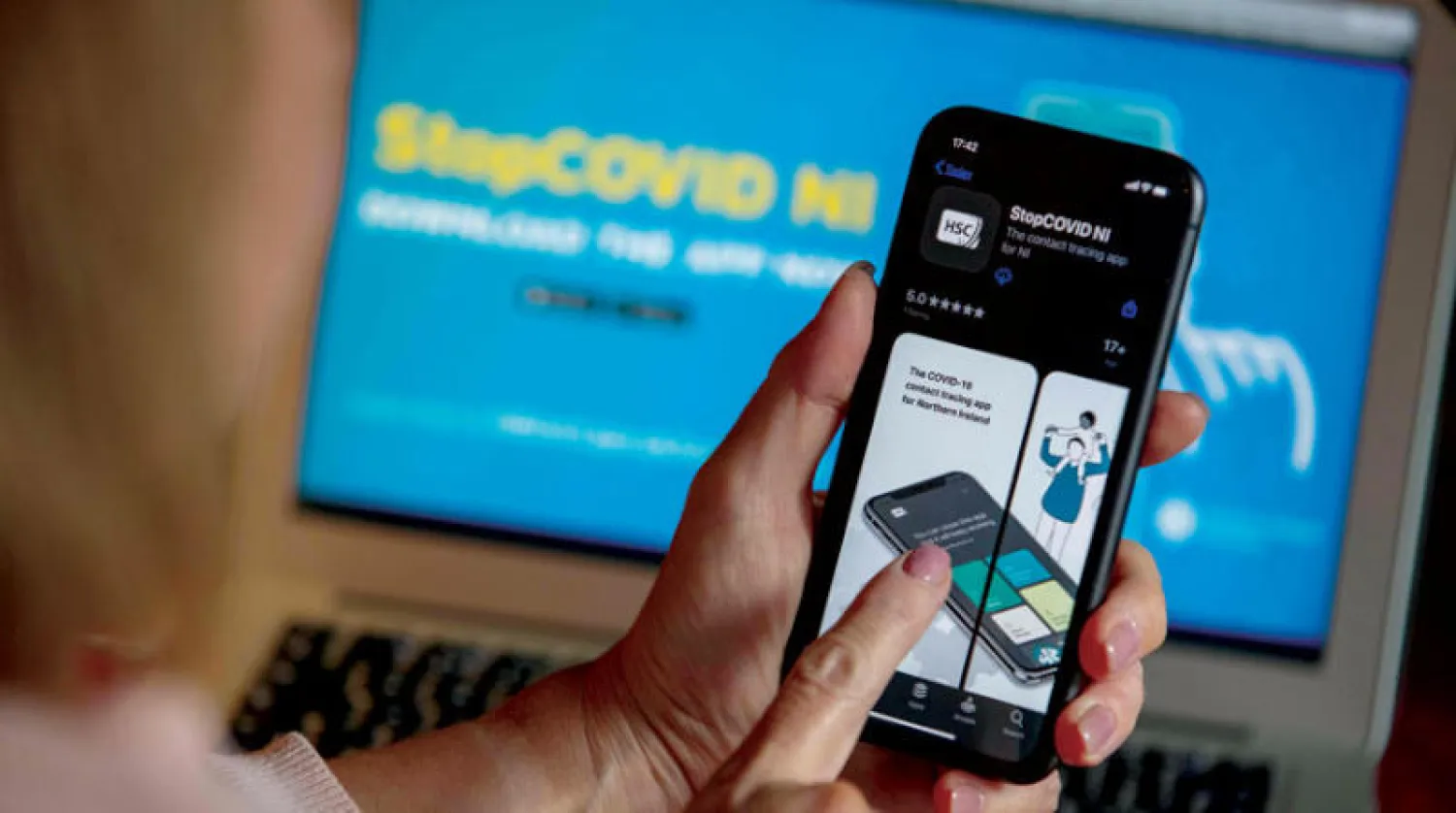 سيدة تحمّل تطبيق تتبع «كوفيد - 19» في باليمينا بآيرلندا الشمالية (أ.ف.ب)
