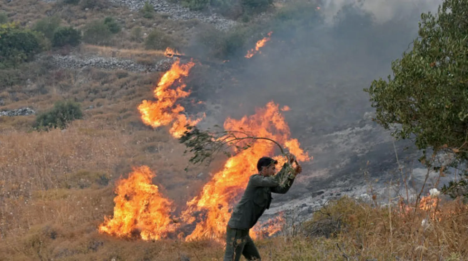 رجل يحاول إطفاء النيران في ريف حماة وسط سوريا (أ.ف.ب)