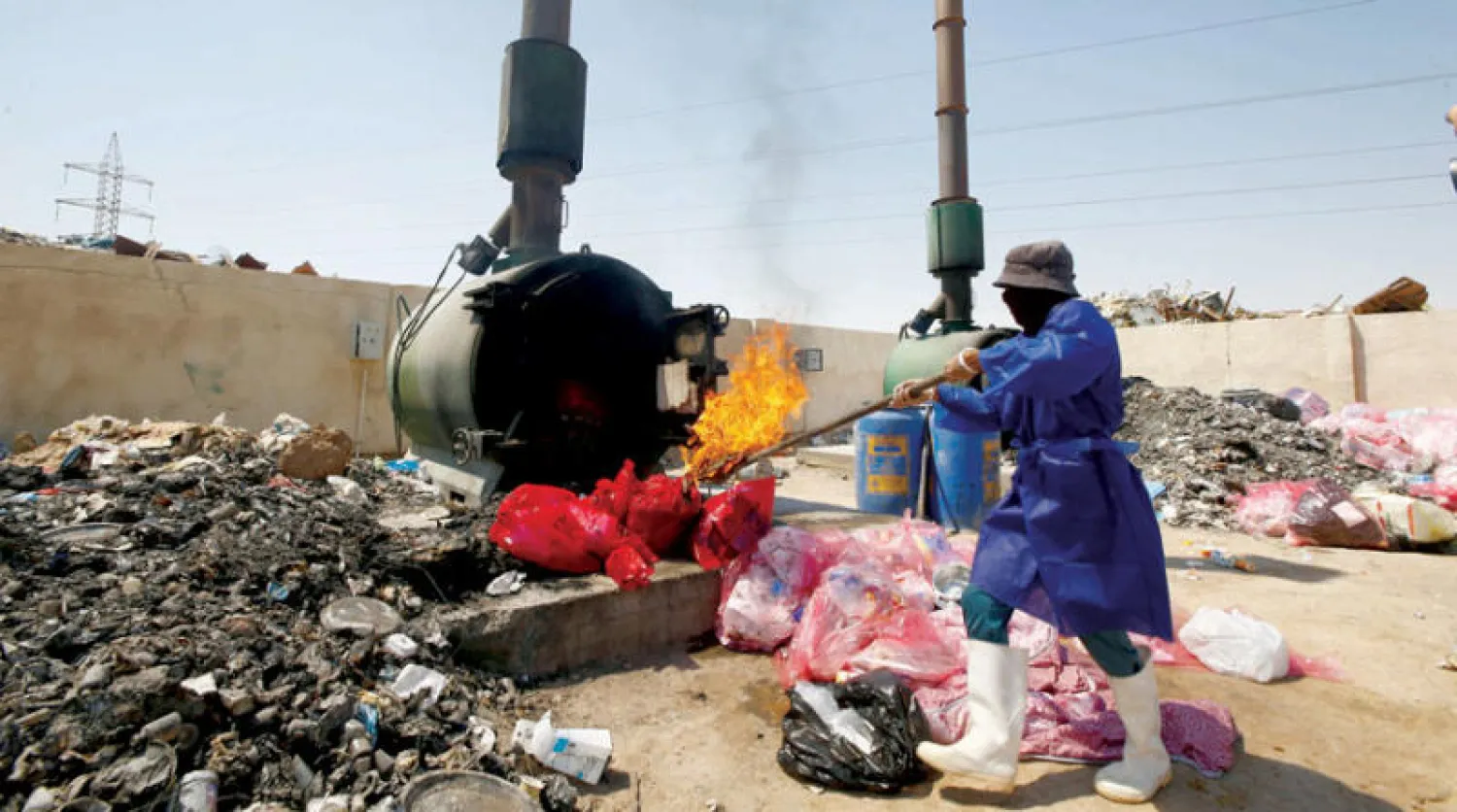 عامل عراقي يحرق نفايات مستشفى يعالج مرضى «كوفيد 19» بالنجف في 27 أغسطس الماضي (رويترز)