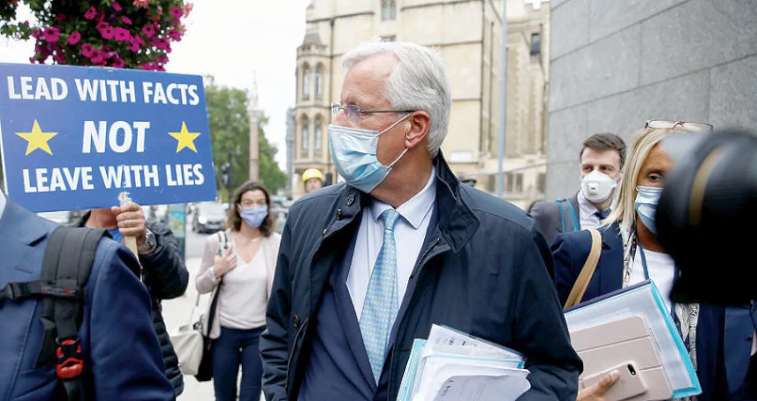 متظاهر بريطاني يرفع لافتة بوجه كبير المفاوضين الأوروبيين ميشال بارنييه أثناء توجهه إلى اجتماع في لندن أمس (رويترز)