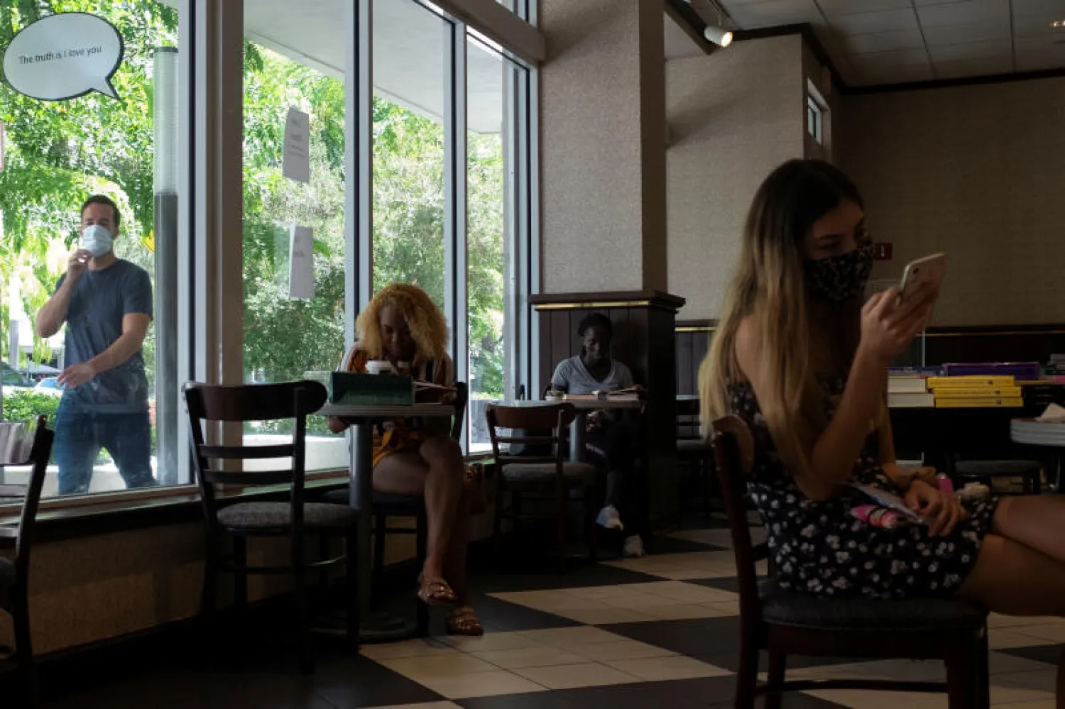 مجموعة من الأشخاص يتناولون المشروبات في مقهى بولاية ميامي الأميركية (رويترز)