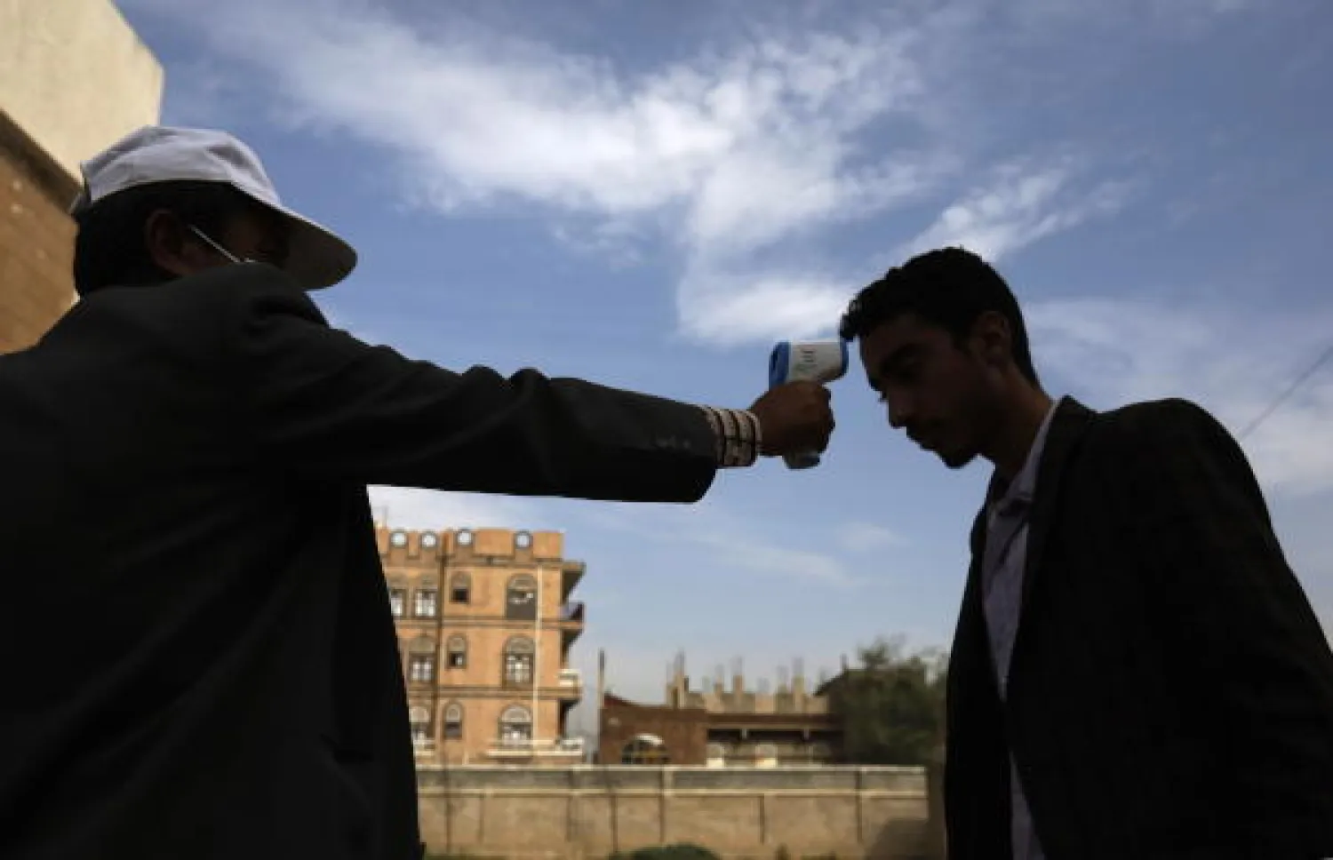 أحد موظفي الصحة يفحص درجة حرارة يمني في صنعاء (إ.ب.أ)