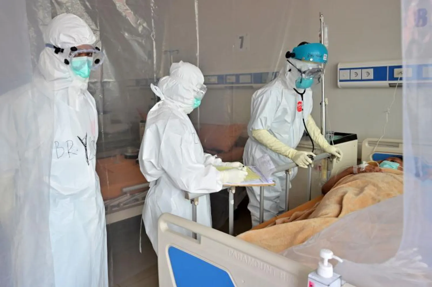 أطباء يتفقدون مريضاً مصاباً بكورونا في أحد مستشفيات إندونيسيا (أ.ف.ب)