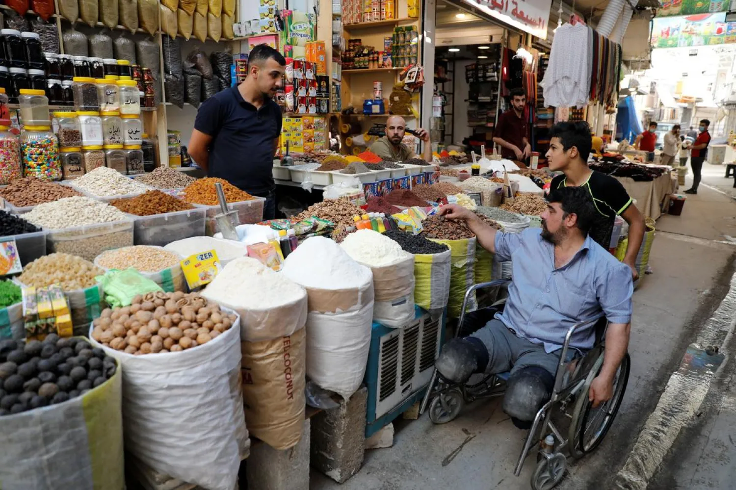 Mohammed Sattar, an Iraqi man who says that he lost his both legs during the battle to retake Mosul from ISIS militants, sits in a wheelchair as he looks at the goods outside a shop in the old city of Mosul, Iraq, August 31, 2020. REUTERS/Khalid al-Mousily