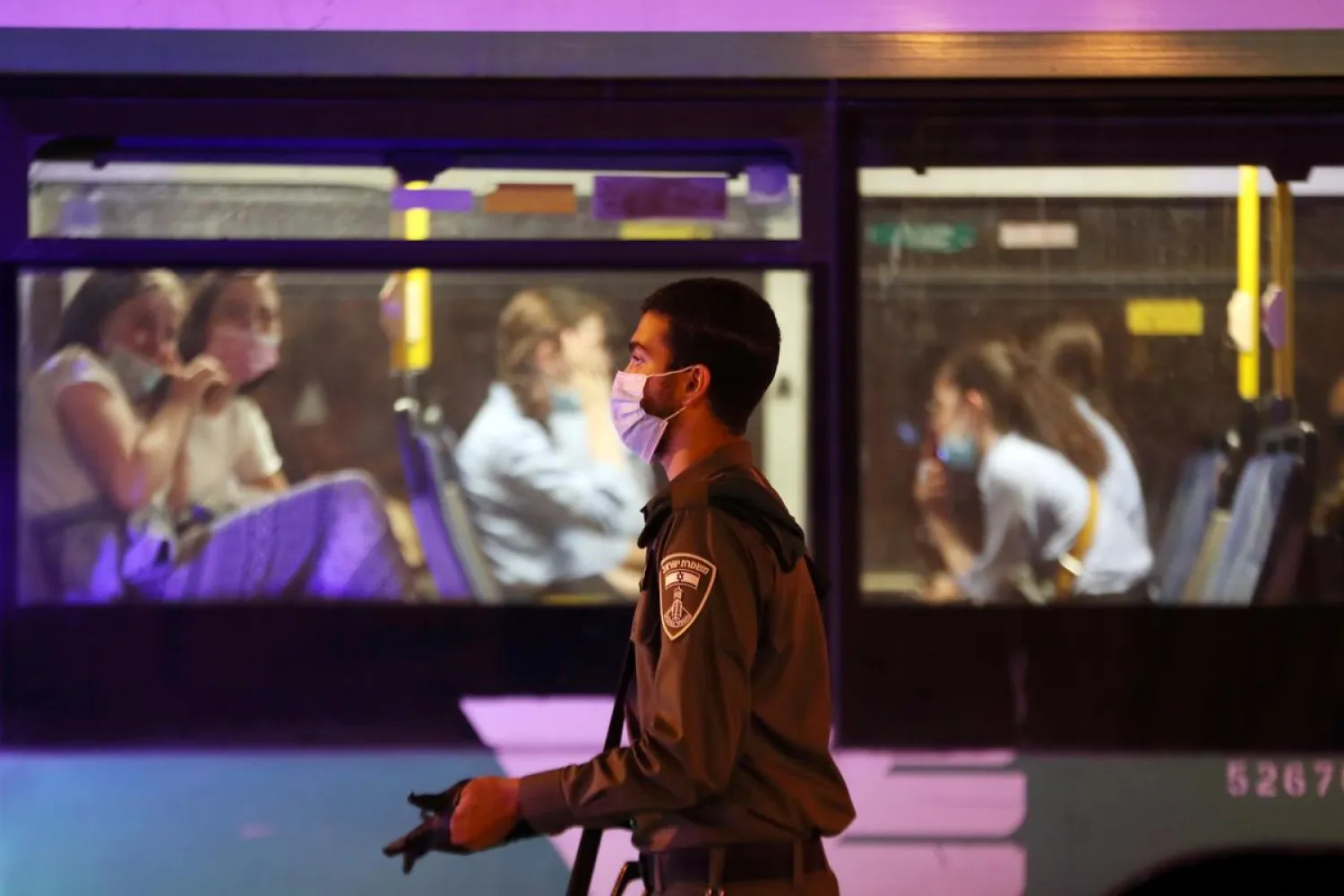 An Israeli border police officer walks next to a bus near a roadblock during enforcement of a government decision to impose nightly curfews in dozens of towns and neighborhoods to stem the spread of the coronavirus disease (COVID-19), in Jerusalem September 8, 2020. REUTERS/Ronen Zvulun

