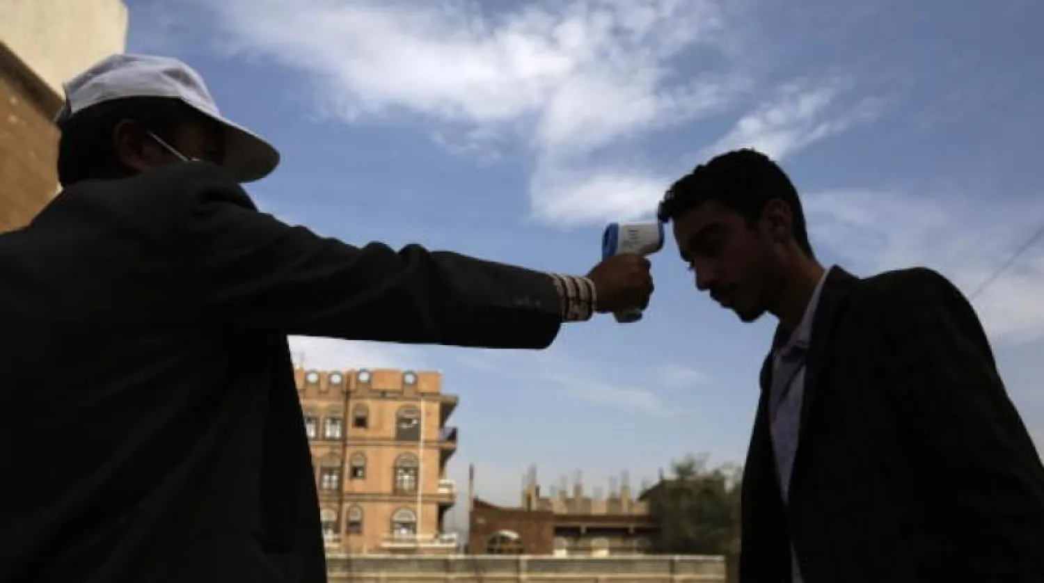 یک کارمند بخش بهداشت در حال بررسی دمای یک شهروند یمنی در صنعا (EPA)
