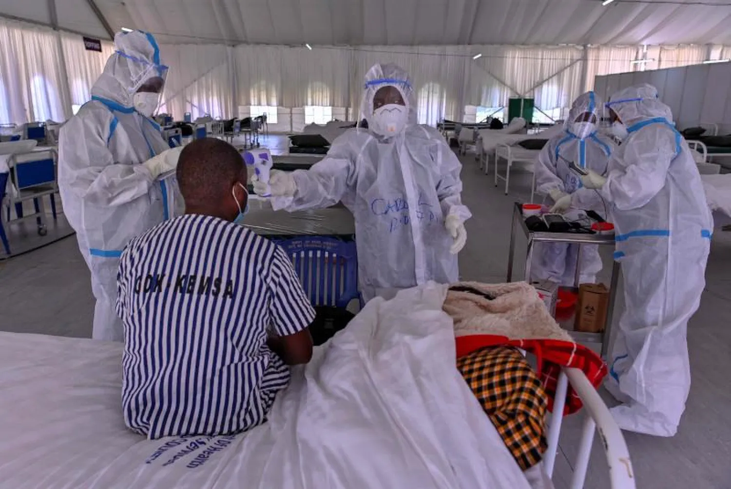فريق طبي يتفقد مريضاً مصاباً بـ«كورونا» بأحد المراكز الصحية في كينيا (أ.ف.ب)