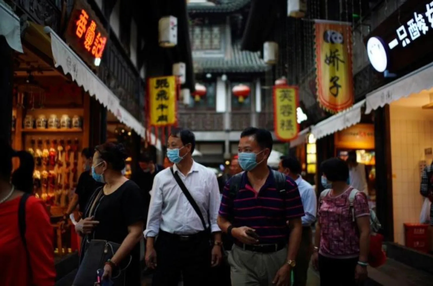 أشخاص يرتدون أقنعة الوجه يسيرون في شارع جينلي القديم في مدينة تشنغدو بمقاطعة سيتشوان (رويترز)