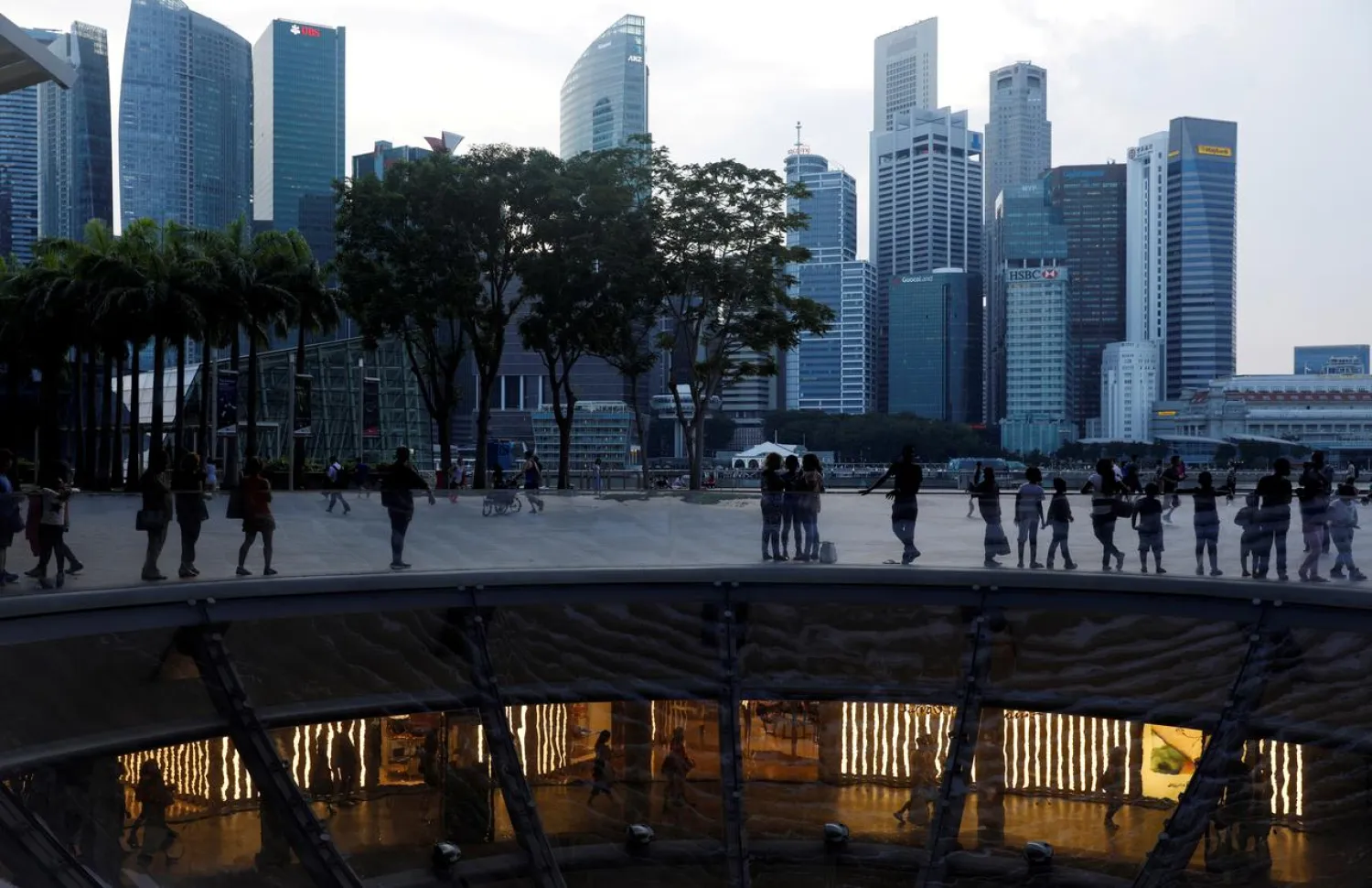 FILE PHOTO: People pass the skyline of the central business district along the Marina Bay Promenade in Singapore April 10, 2017. REUTERS/Edgar Su