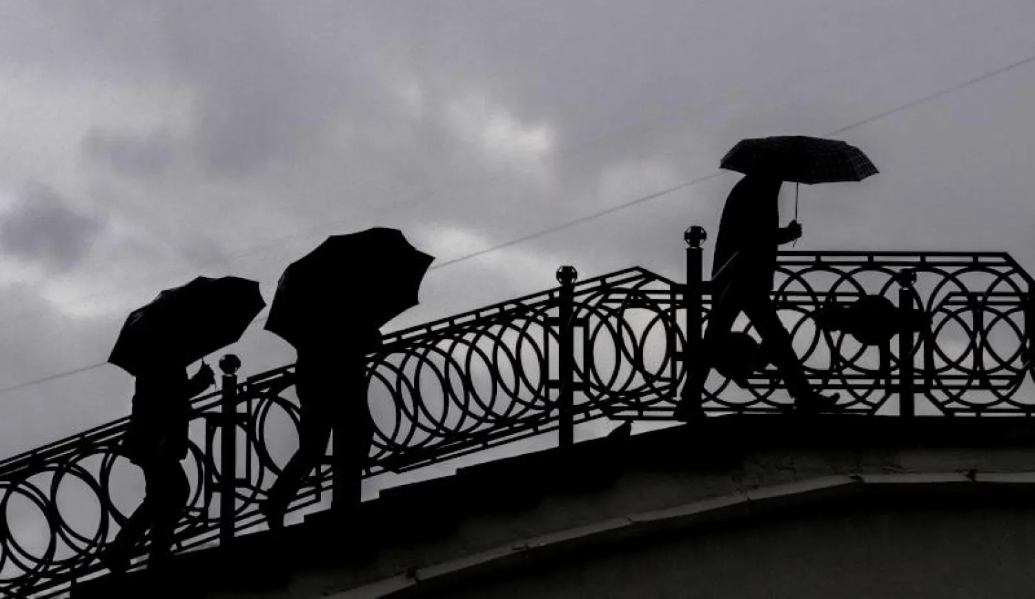 يحتمون من المطر في موسكو (أ.ف.ب)