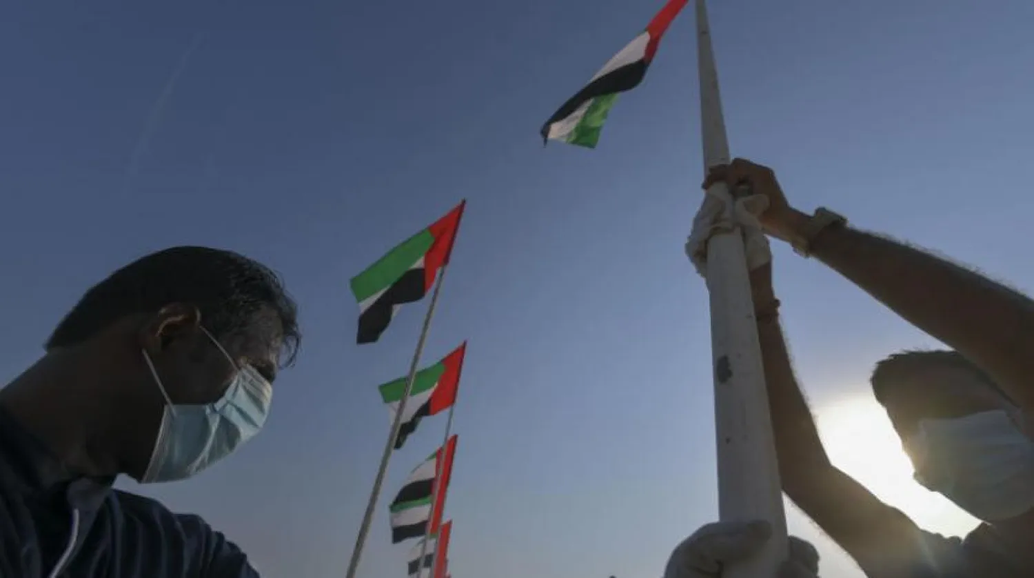 İki yetkili Dubai'deki bir plajda ülkenin bayrağını asıyor (AFP)
