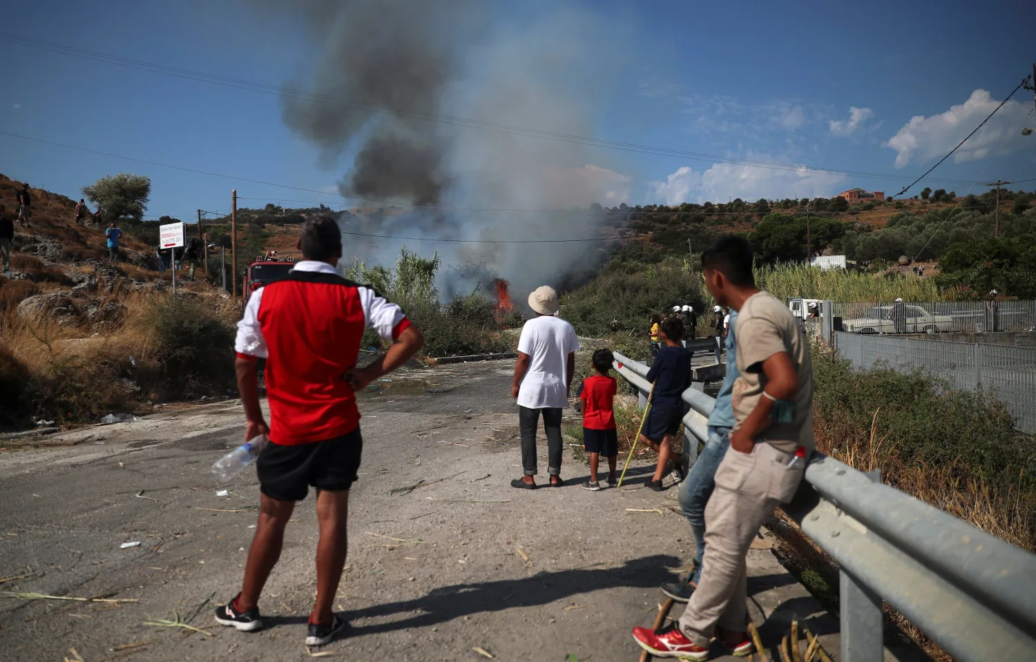 Refugees and migrants from the destroyed Moria camp look at a fire that was lifted up during a protest after the news about the creation of a new temporary camp, on the island of Lesbos, Greece September 12, 2020. REUTERS/Alkis Konstantinidis